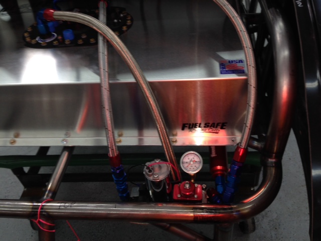 Pump mounted behind tubing with NASCAR style breakaway check valve for crash protection