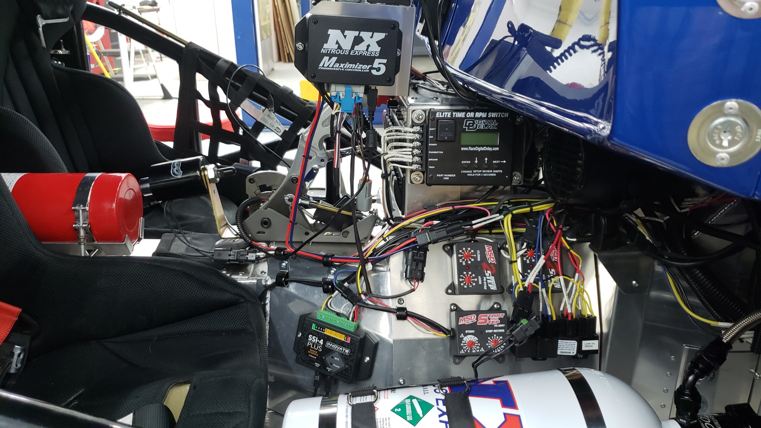 This is a more complex system than the basic install most folks do.  There are many safeguards I built into it to prevent engine damage.  

The engine must actually be running between 4000 & 6400 RPM, the TPS must be at or above 80% (I added a TPS to my QFT carb), the oil & fuel pressure must be above the min set point, the AFR must be between a user set range (I have it set for 11.5 & 14.0), and the system is disabled while the trans brake is on then enabled 0.1-sec after launch to ensure it never sprays when the two-step is engaged (that would be bad).  

The controller also pulses the solenoids to ramp the nitrous to a set point from 20% to 100% while holding the adjustable AFR set point (I programmed in 13.0:1), and triggers the MSD ignition retard based on the amount of nitrous injected (~2-deg for each 50-shot). 

The ramp is adjustable so it can bring the spray in based on a number of factors (time, speed, RPM, boost, TPS, ...) and can ramp it up or down or a combination of both up, down, up again.  

There is sure a lot of electronic gizmos in a modern Super Pro drag racer.  And you quickly run out of space in one of these little cars.